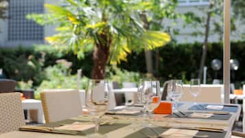 Mesa de comedor al aire libre con sillas, copas de vino y una carta.