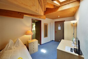 Cozy retreat with a single bed, dresser, and desk area.