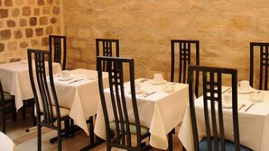 A restaurant with tables set for dining, featuring a stone wall backdrop. - Villa Du Maine (Paris)