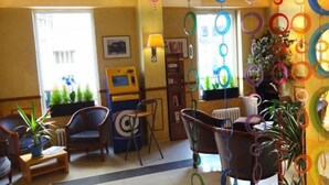 A hotel lobby with a reception desk, seating area, and decorative hanging elements. - Villa Du Maine (Paris)