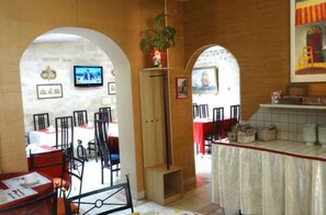A restaurant with a central bar, tables, chairs, and a TV screen. - Villa Du Maine (Paris)