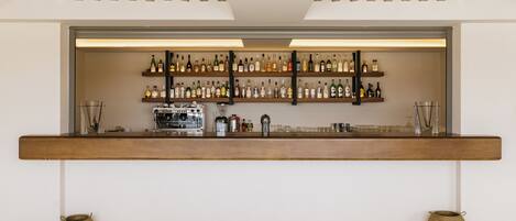 A bar area with shelves of liquor bottles, a coffee machine, and two woven baskets on the floor.