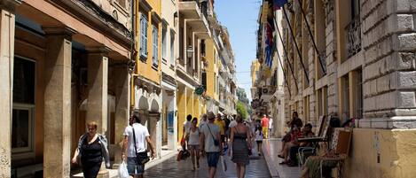 A pedestrian street lined with historic buildings, some with balconies and outdoor seating.