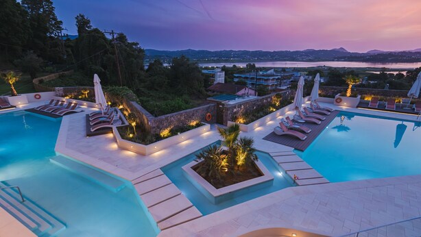 A pool area with multiple sun loungers and a view of the surrounding landscape. - Divani Corfu Palace (Corfu)