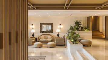 A modern lobby with a sofa set, two lamps, a mirror, and a staircase.