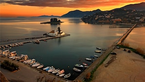 A marina with boats docked, a pier, and a small island with a building. - Divani Corfu Palace (Corfu)