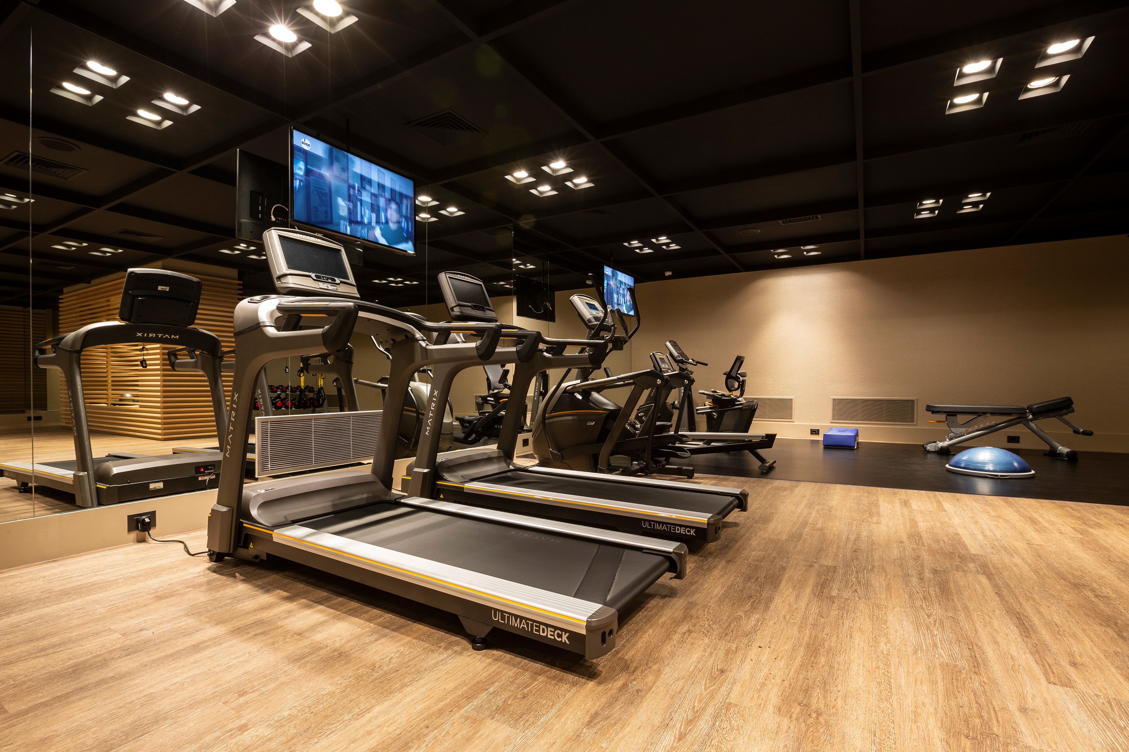 Un gimnasio con cintas de correr, una bicicleta estática y una máquina de remo.
