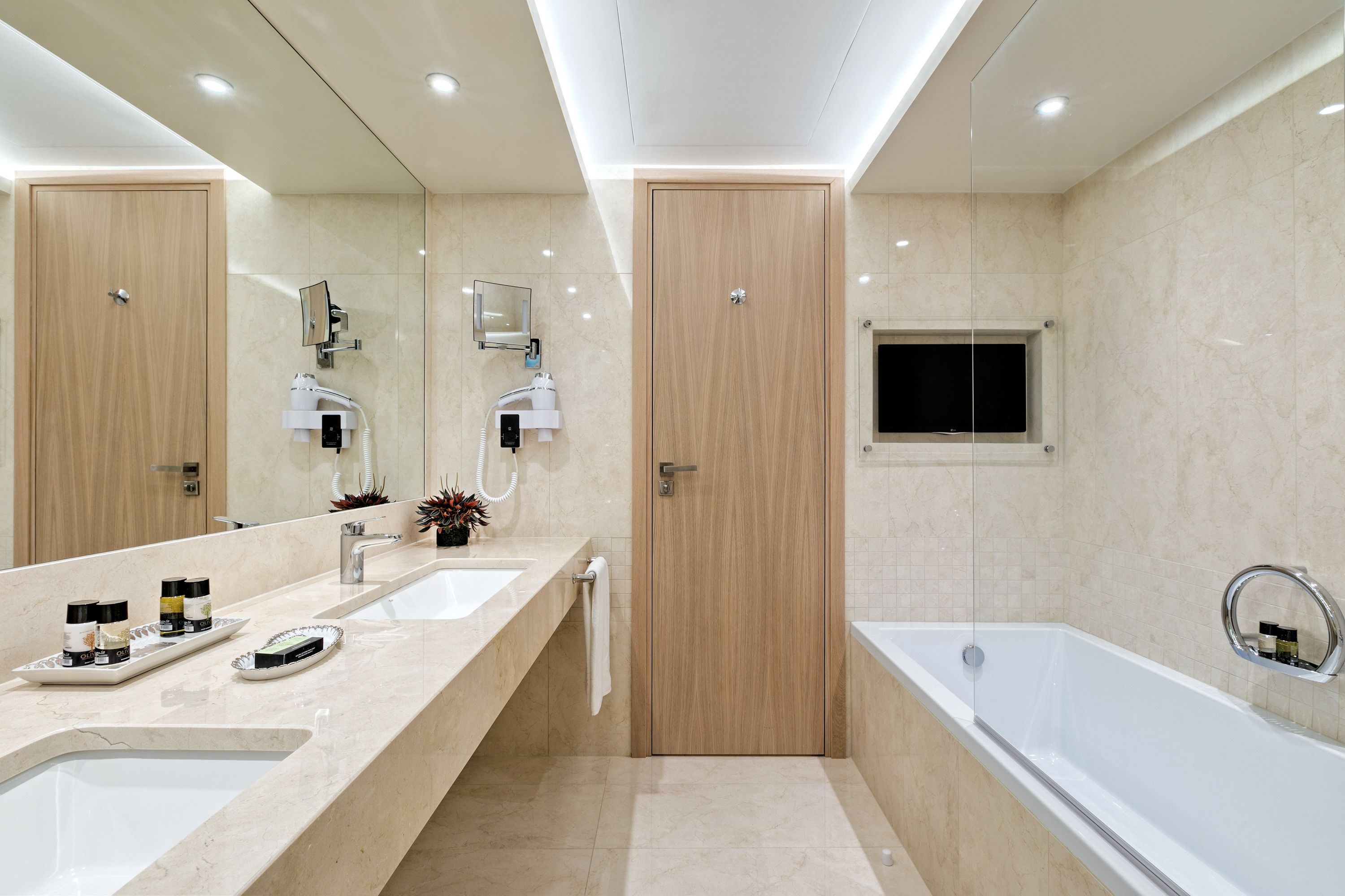 Un bagno moderno con due lavabi, uno specchio grande, una vasca e una porta in legno.