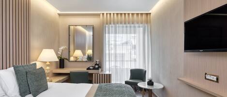 A hotel room with a bed, bedside table, lamp, chair, desk, mirror, TV, and a window with curtains.