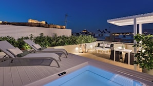 Una terrazza sul tetto con idromassaggio, poltrone relax e una pergola.