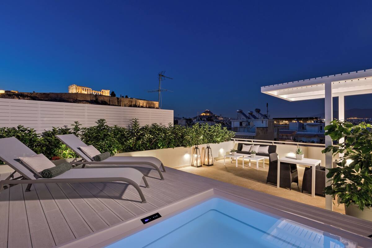 A rooftop terrace with a hot tub, lounge chairs, and a pergola.