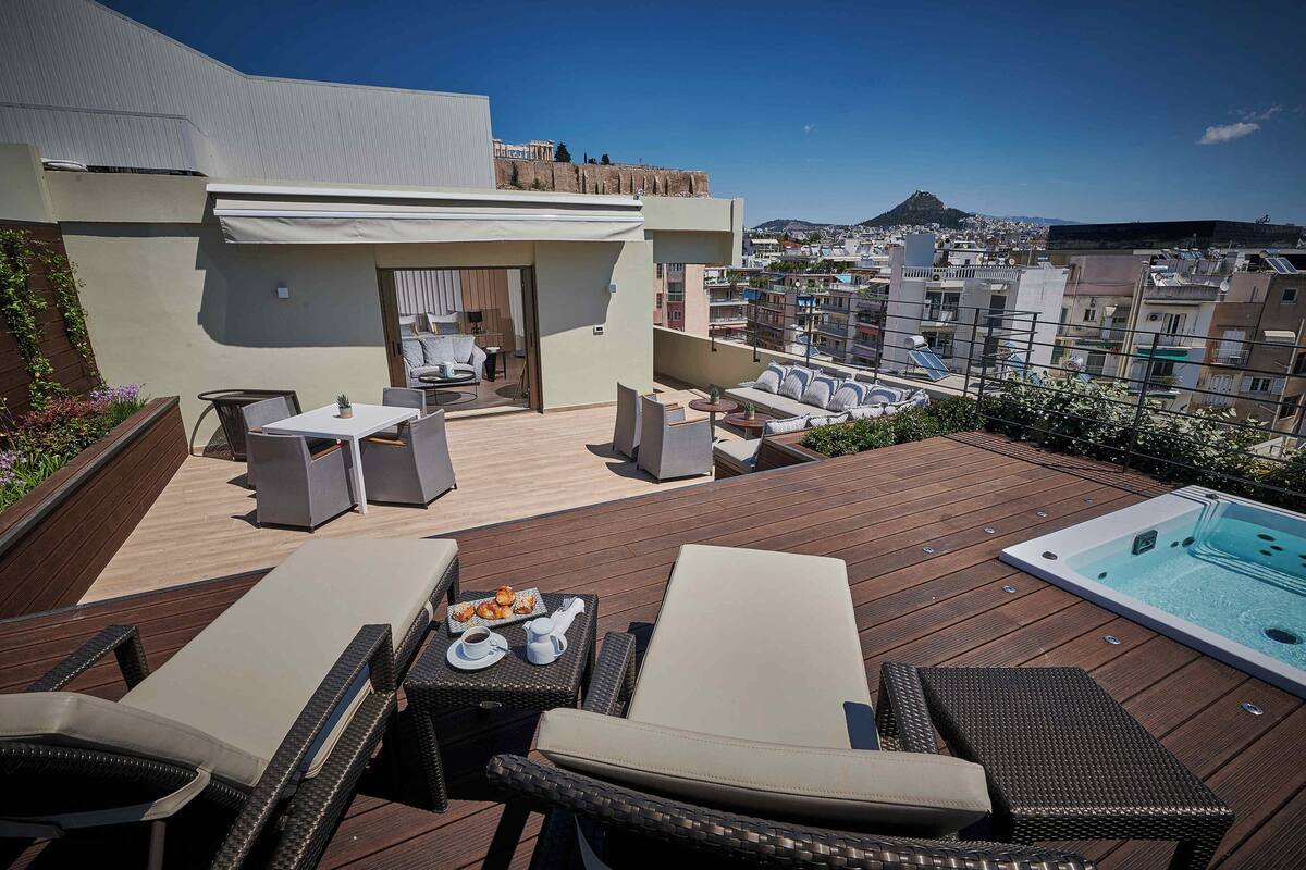 A rooftop terrace with outdoor seating, a hot tub, and a view of the cityscape.