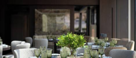 Un restaurant avec des tables rondes, des chaises et une plante décorative placée au centre.