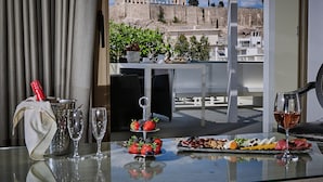 Un tavolo con una bottiglia di champagne, bicchieri e un vassoio di frutta, con vista su rovine antiche.