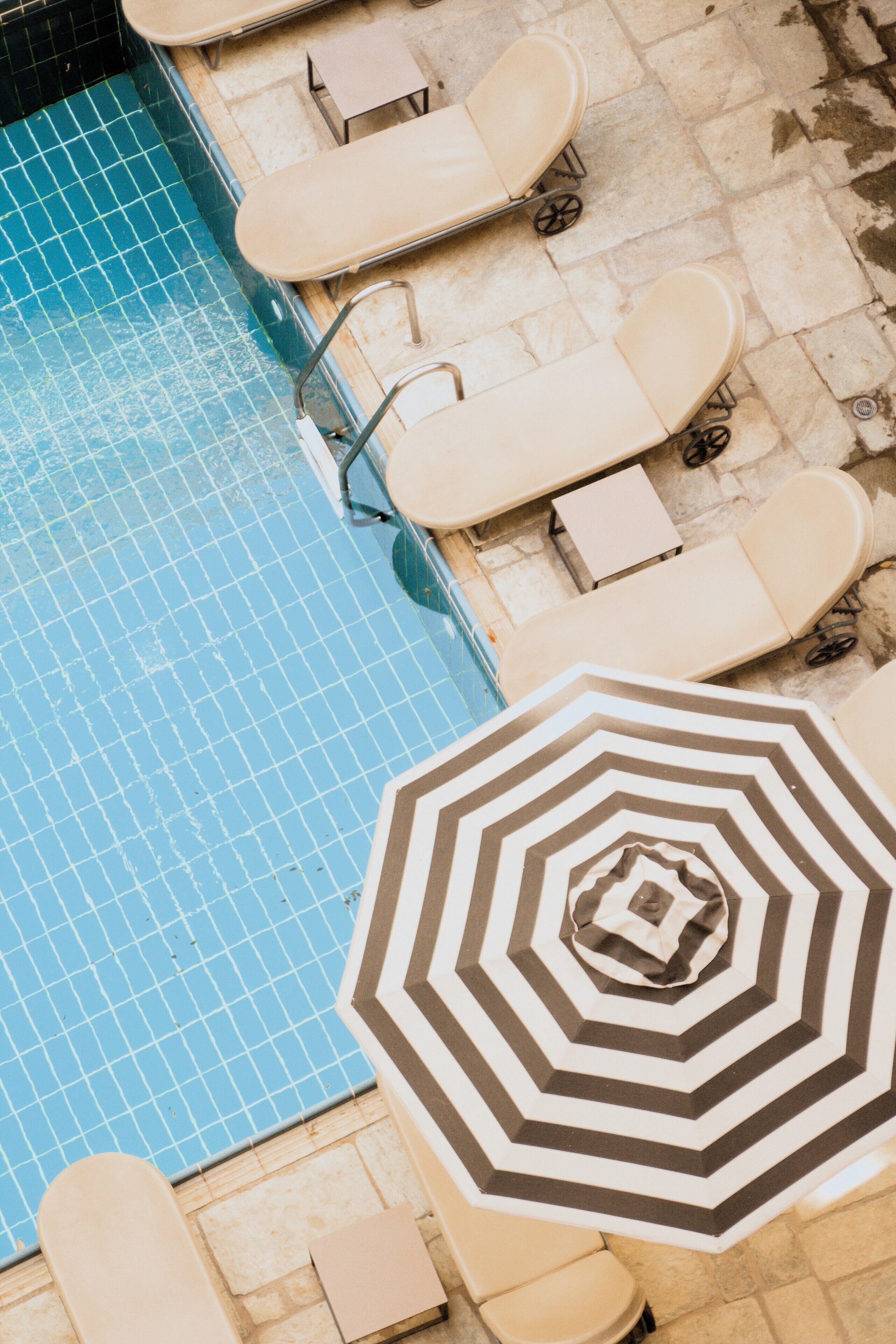 A pool area with lounge chairs and a patterned umbrella.