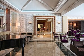 A spacious lobby with a grand piano, seating areas, and a patterned wall. - Rodos Park - Small Luxury Hotels of the World (Rhodes)