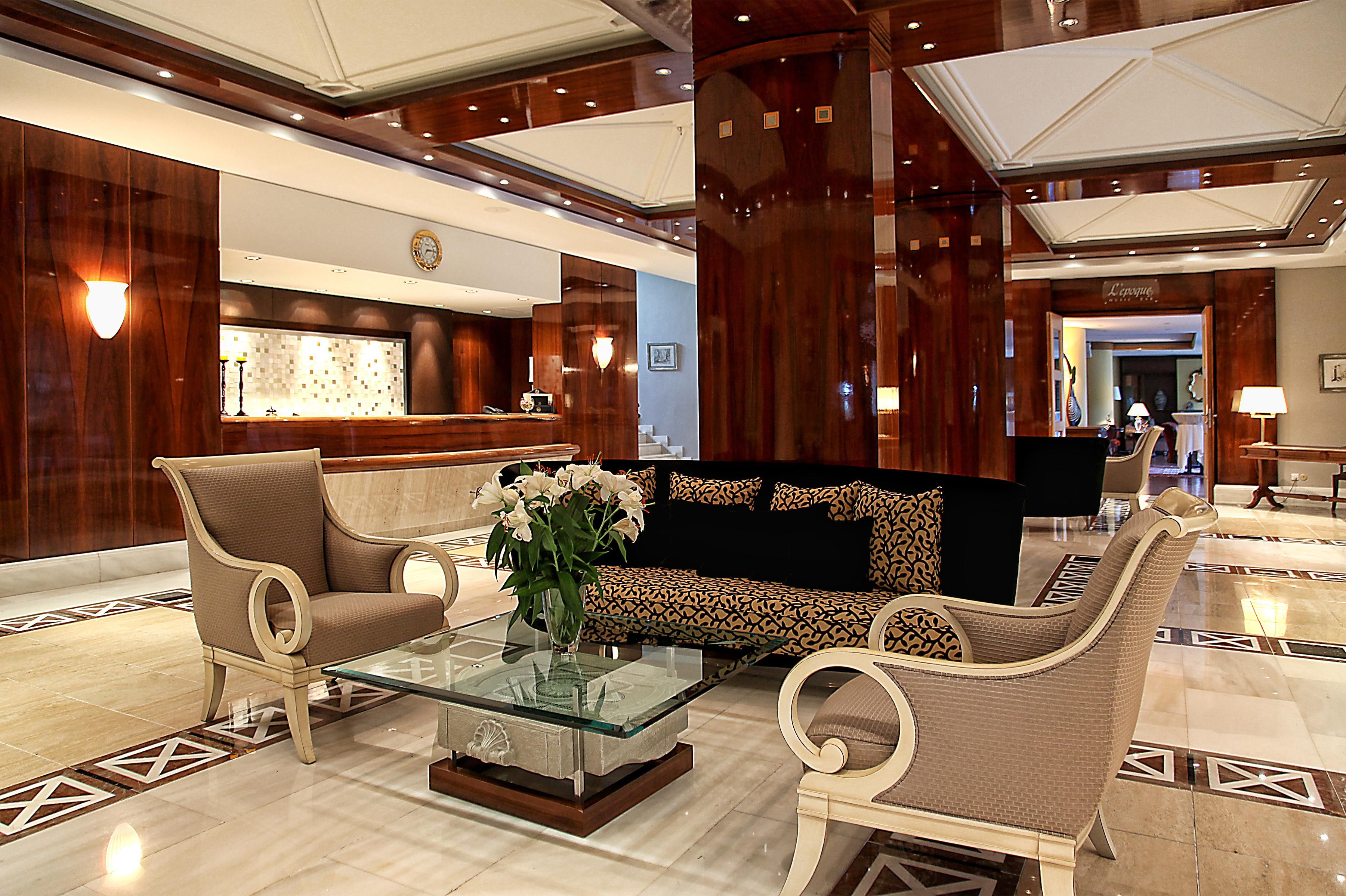 Un hall con mostrador de recepción, zona de estar y un jarrón decorativo con flores.