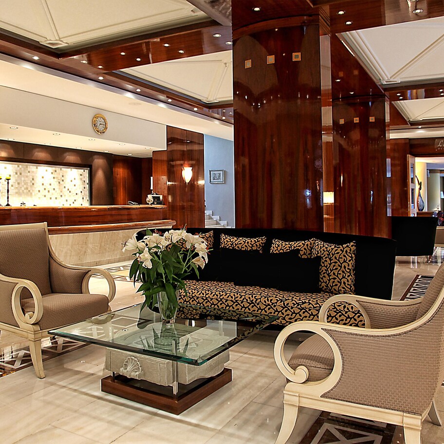 A lobby with a reception desk, seating area, and a decorative vase with flowers.