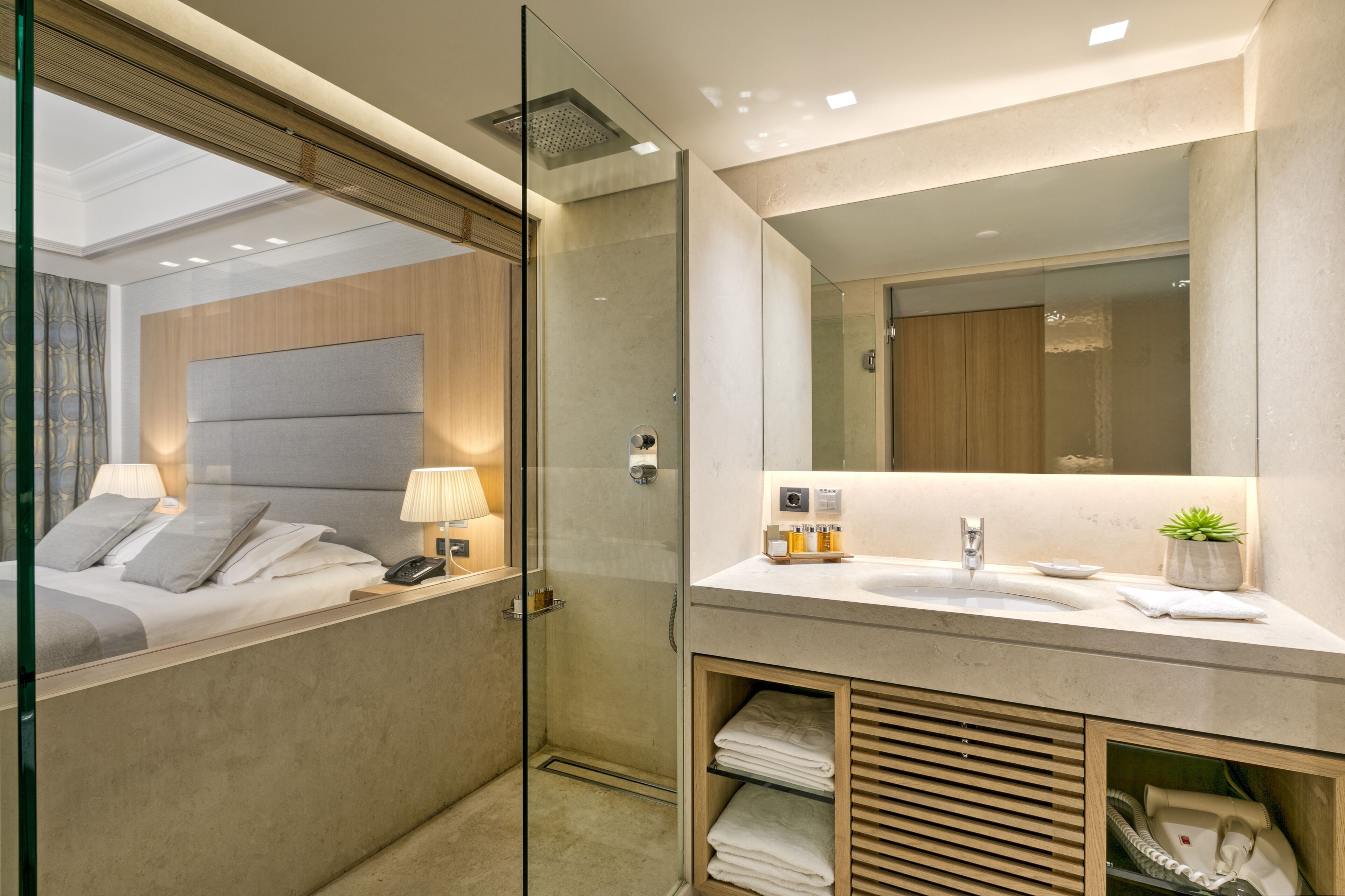 A modern bathroom with a glass shower enclosure, a large mirror, and a vanity with a sink and towel rack.