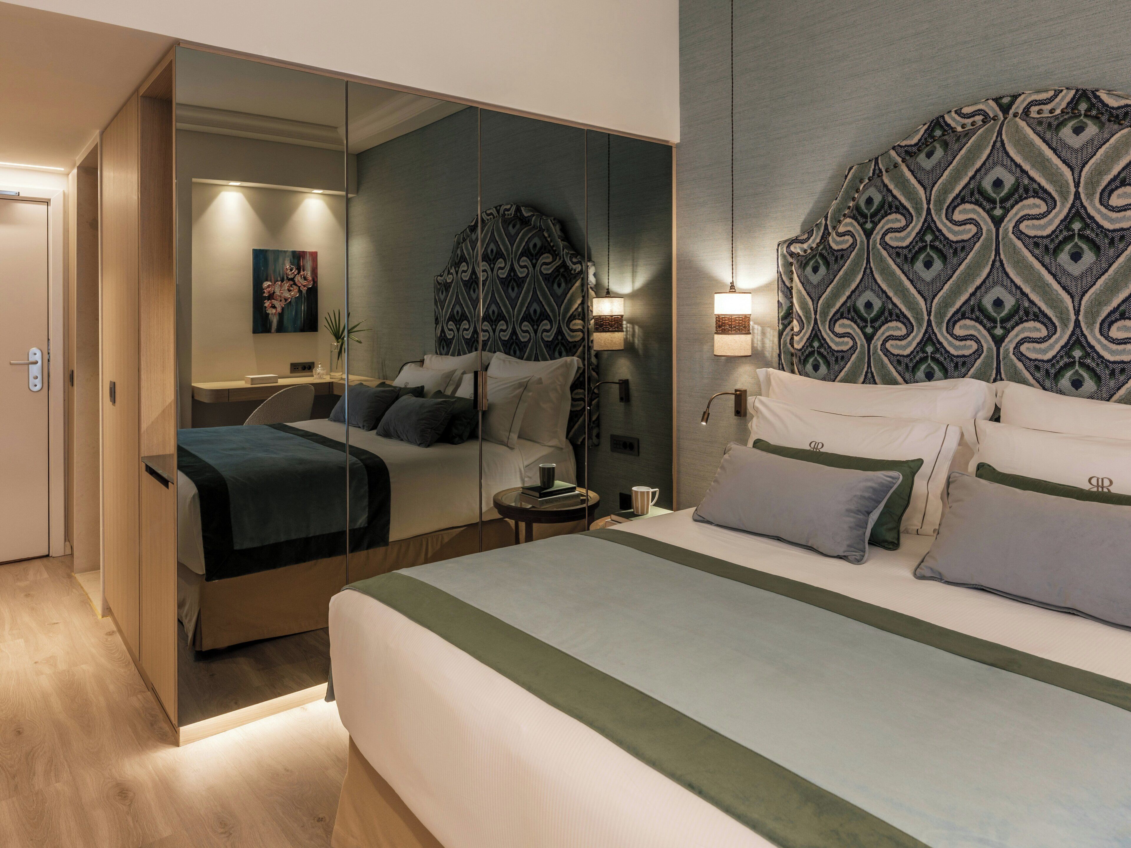 Een moderne hotelkamer met een groot bed, een spiegel en een kamerhoge bekleding met een patroon.