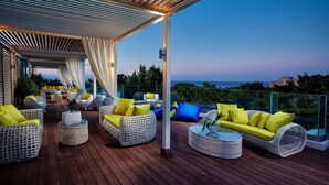 Una terraza exterior con mobiliario de mimbre y cojines, con vistas a un paisaje pintoresco.