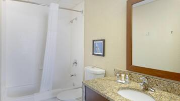 A bathroom with a shower, toilet, sink, and a large mirror.