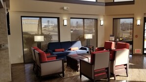 A lobby with a blue sofa, red chairs, and a small table. There are two lamps and a sign that says "EXIT". - Comfort Inn & Suites Wichita Northeast (Wichita)