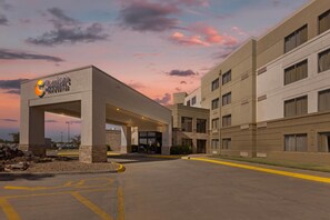 A hotel entrance with a covered area, a parking lot, and a building facade. - Comfort Inn & Suites Wichita Northeast (Wichita)