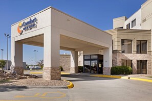 A Comfort Inn & Suites with a covered entrance, stone pillars, and a parking lot.