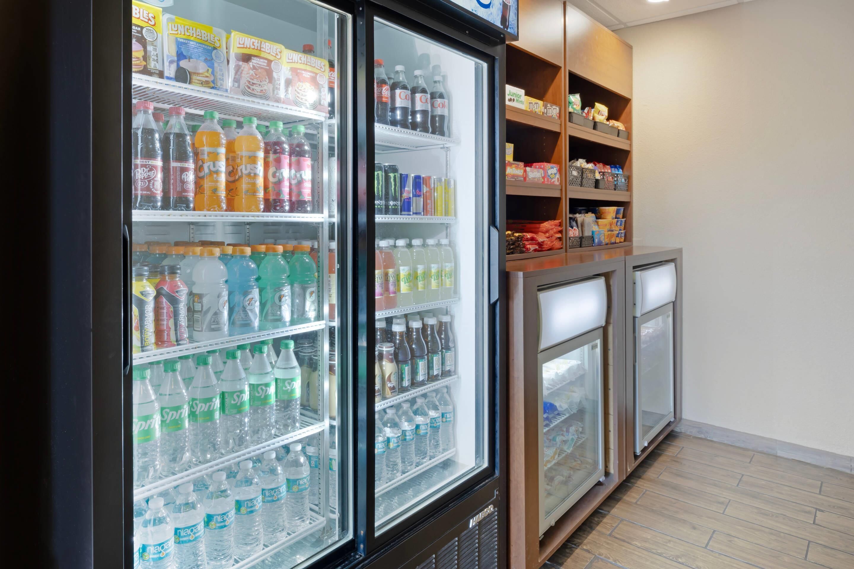 A refrigerated beverage display with various drinks and a shelf stocked with snacks.
