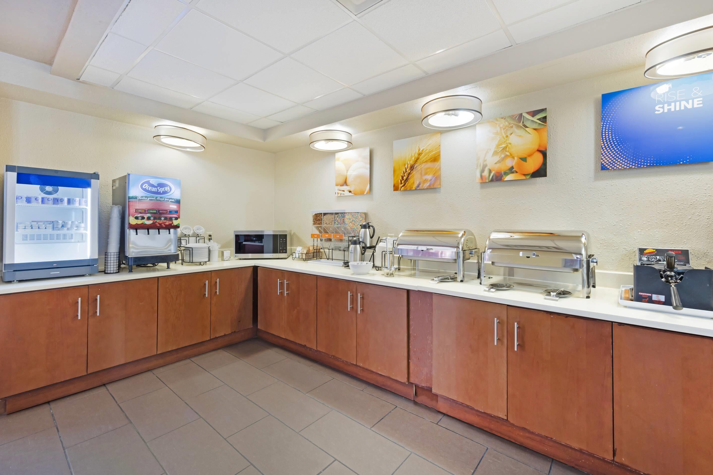 A breakfast area with a refrigerator, coffee machines, and a buffet setup.