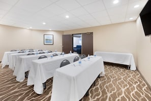Una sala de conferencias con varias mesas, sillas y una pantalla de televisión.