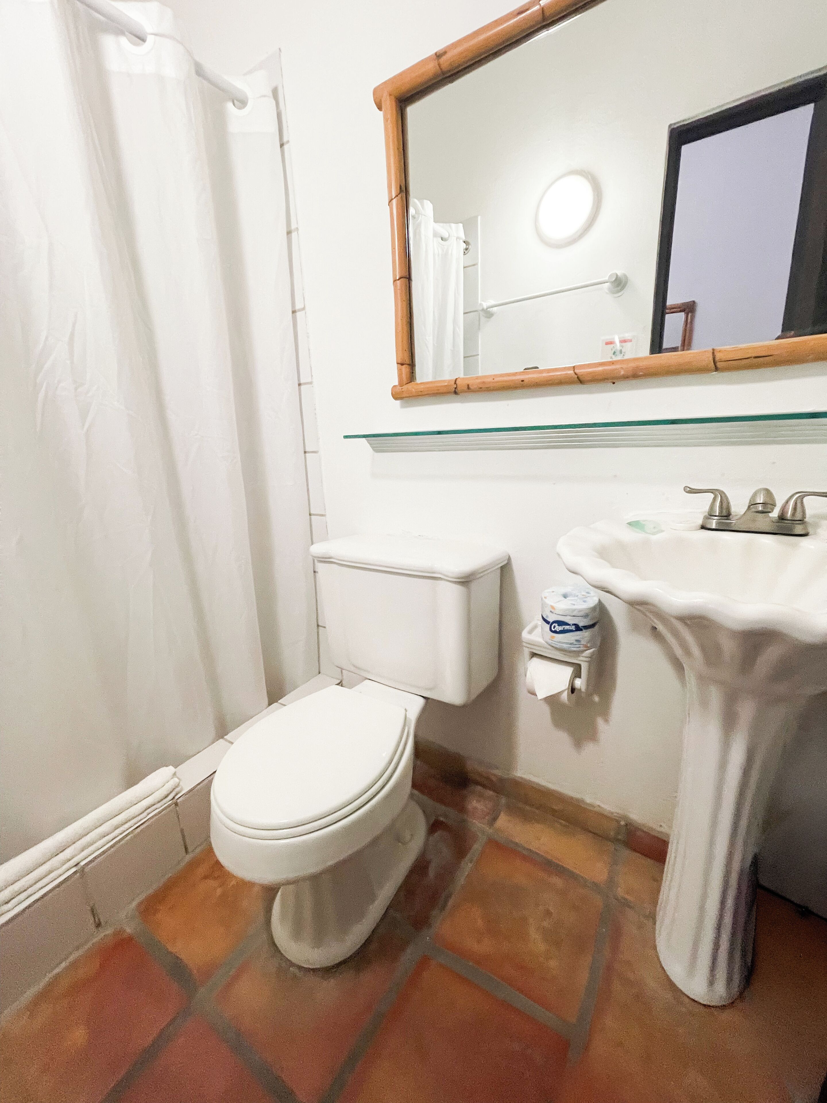 A bathroom with a toilet, sink, and shower curtain.