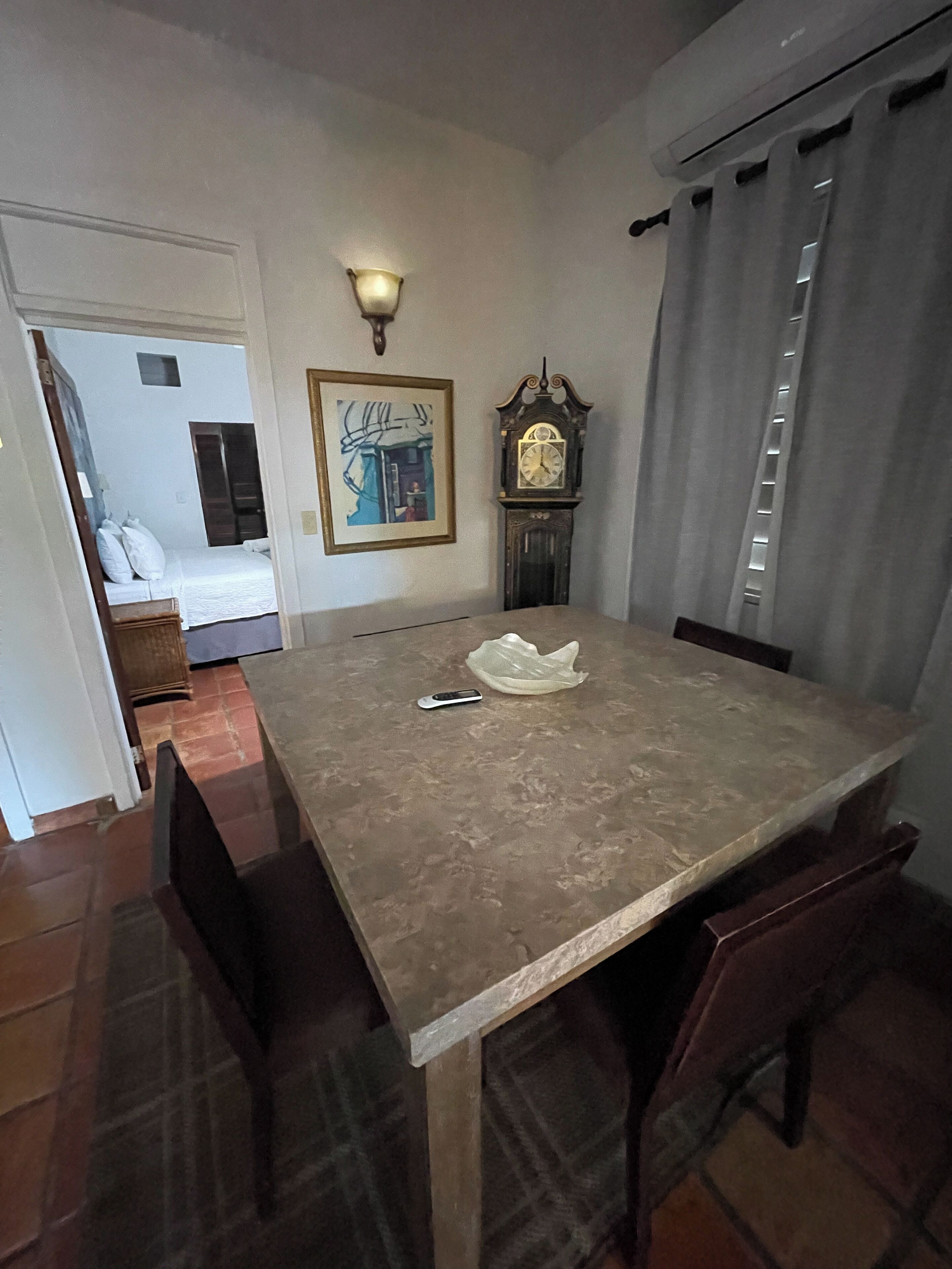 Un espace repas comprenant une grande table, des chaises, une horloge et un luminaire fixé au mur.