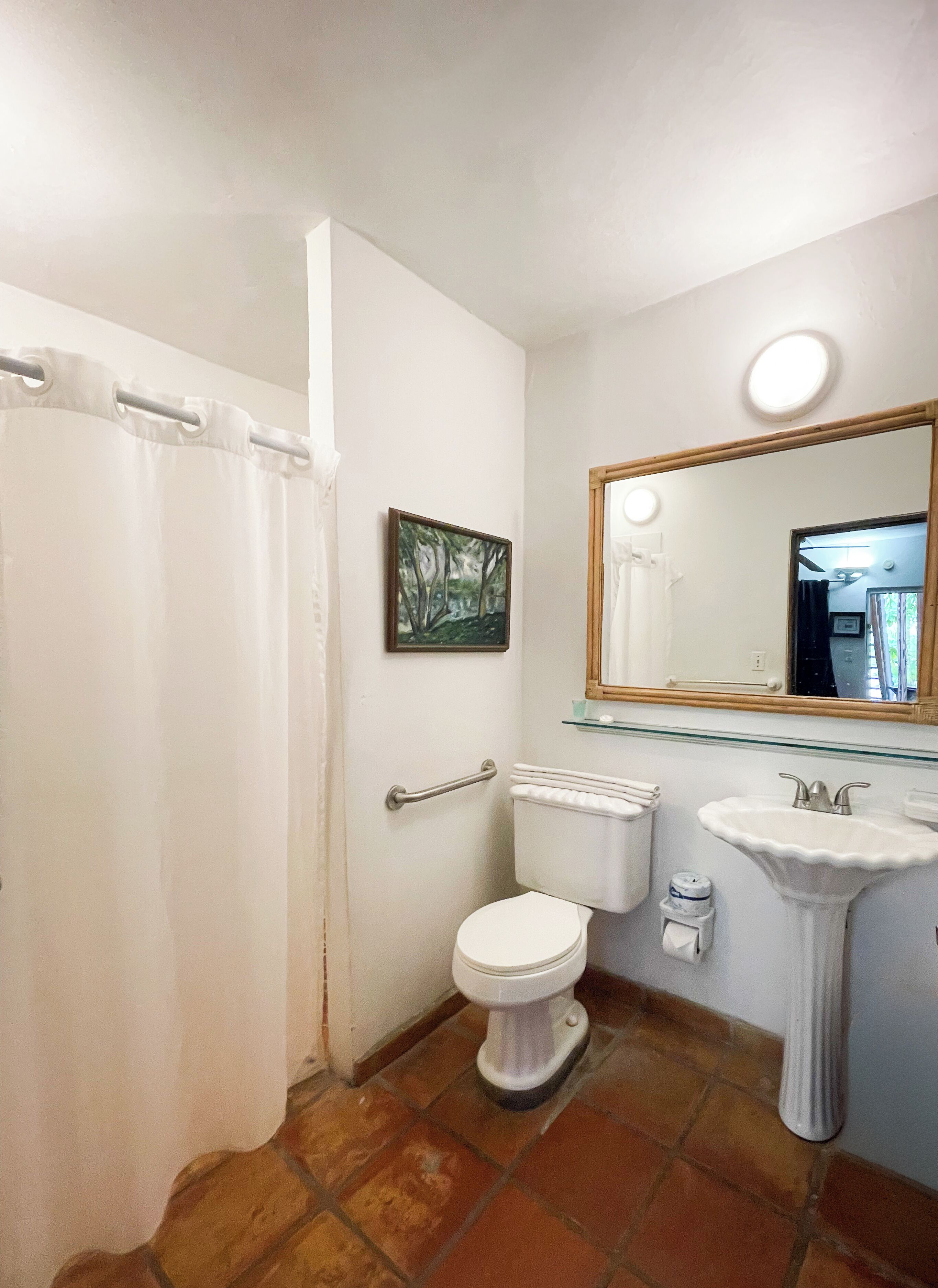 Baño con inodoro, lavamanos y cortina de ducha.
