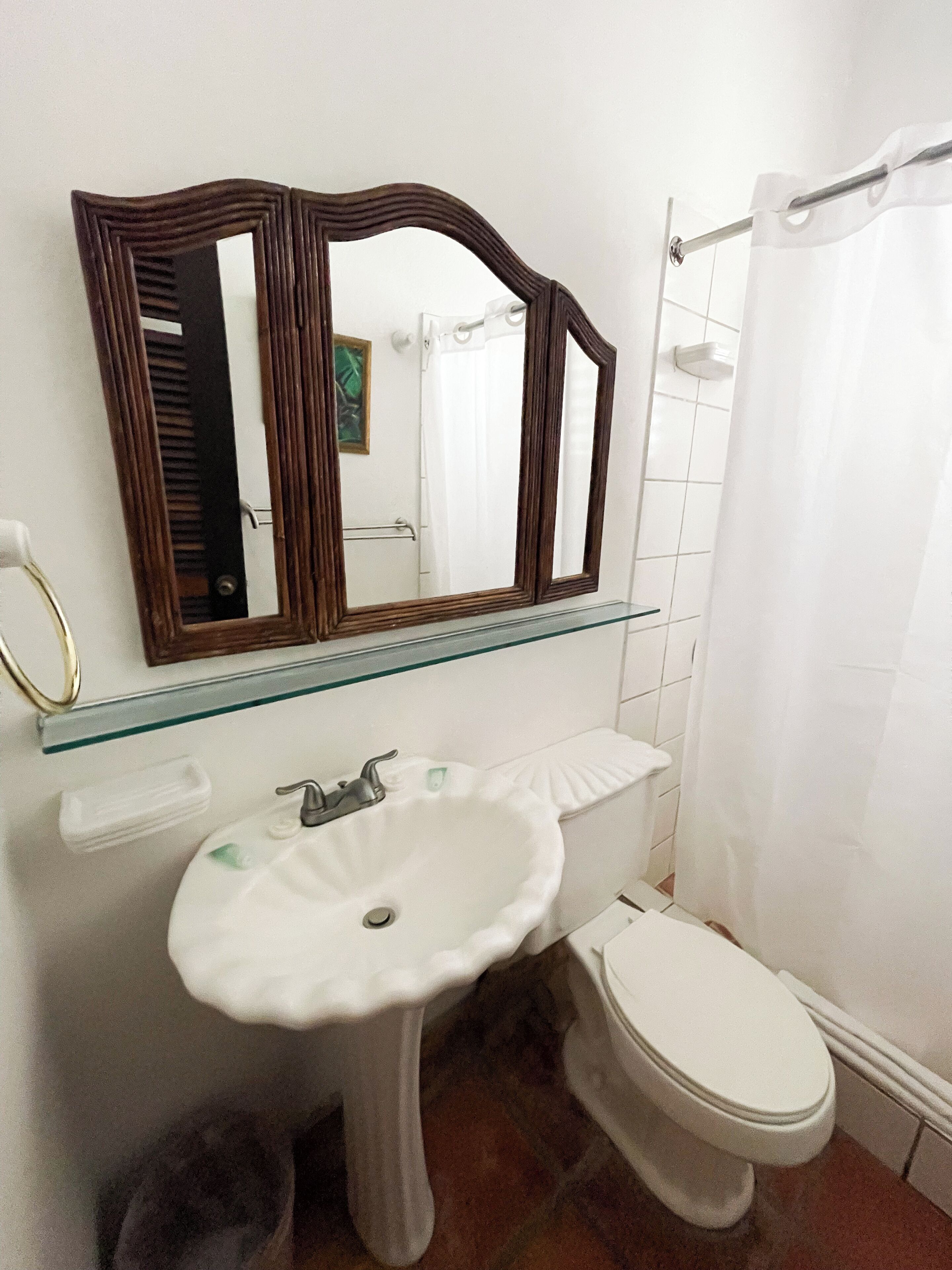 A bathroom with a pedestal sink, a toilet, and a shower curtain.