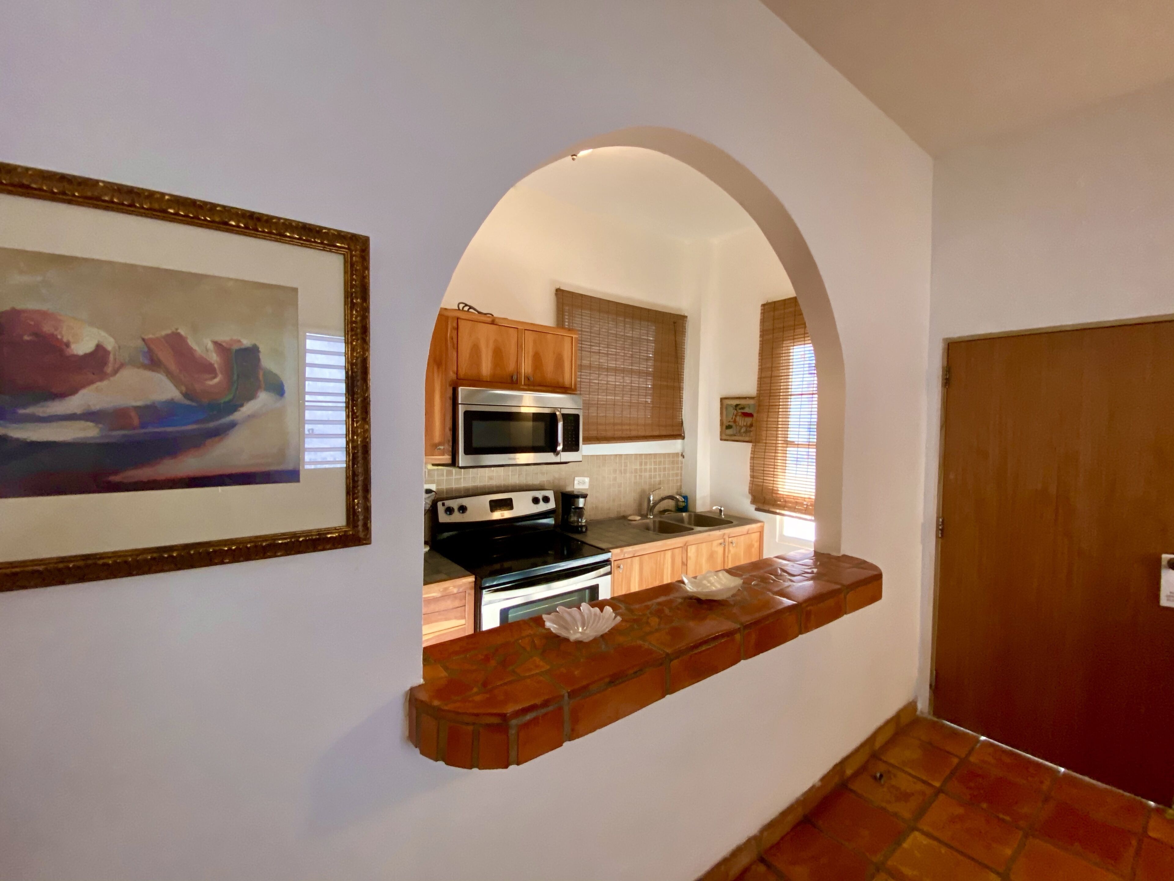 A kitchen with wooden cabinets, a microwave, an oven, and a sink.