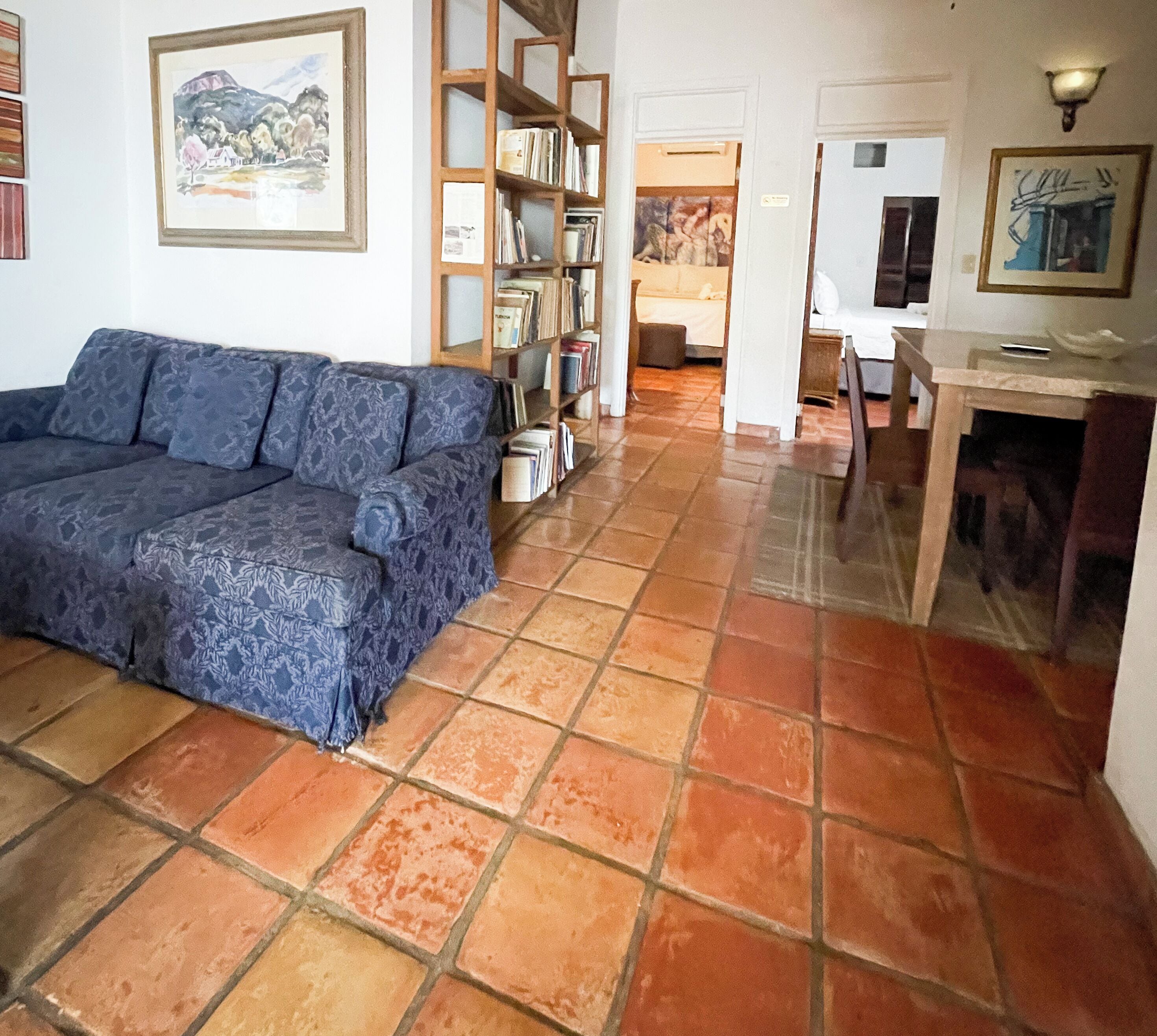 Una sala de estar con un sofá, una estantería y un comedor.