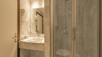 A modern bathroom with a glass-enclosed shower, a vanity with a sink, and a mirror.