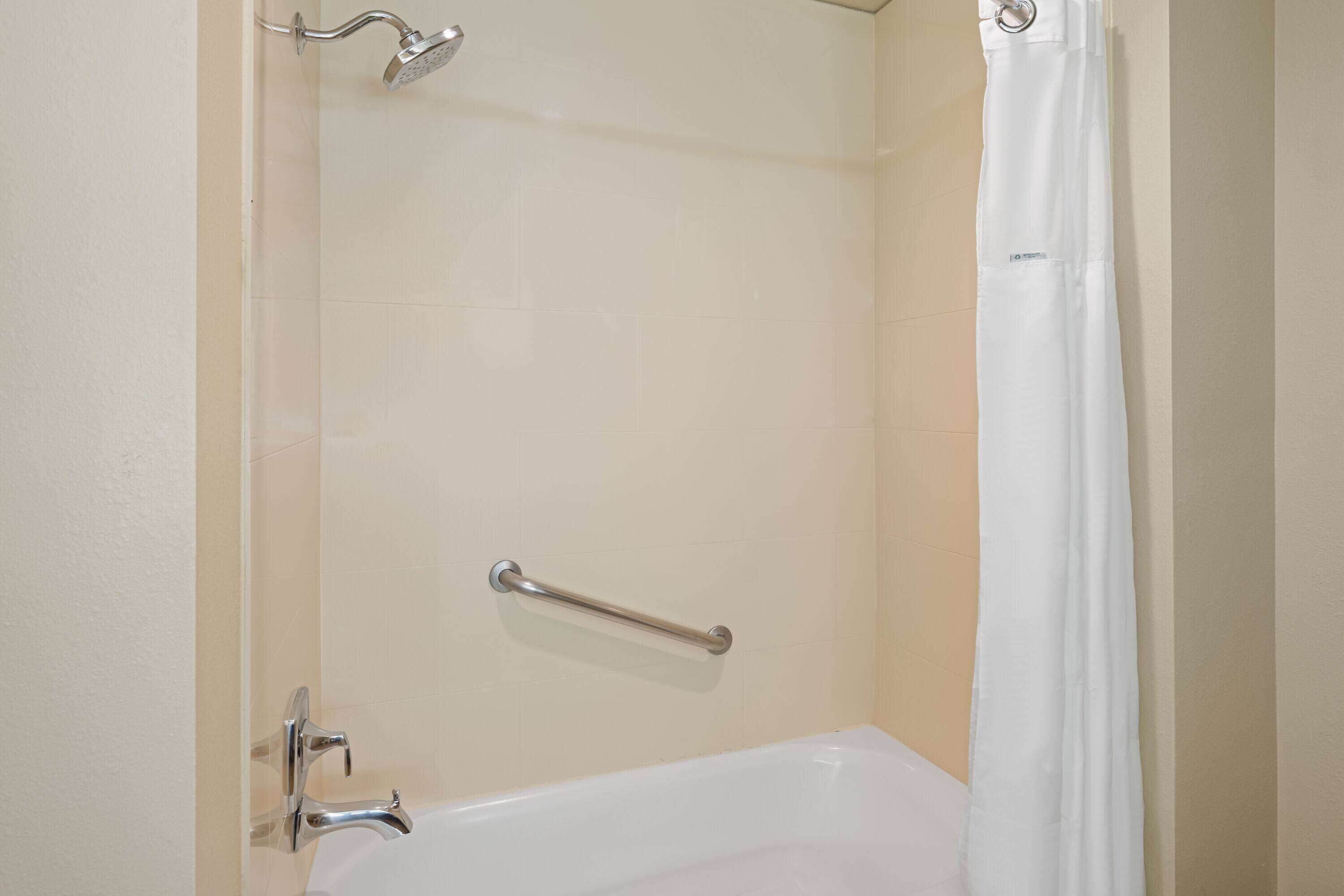 Un baño con bañera, ducha y barandilla.