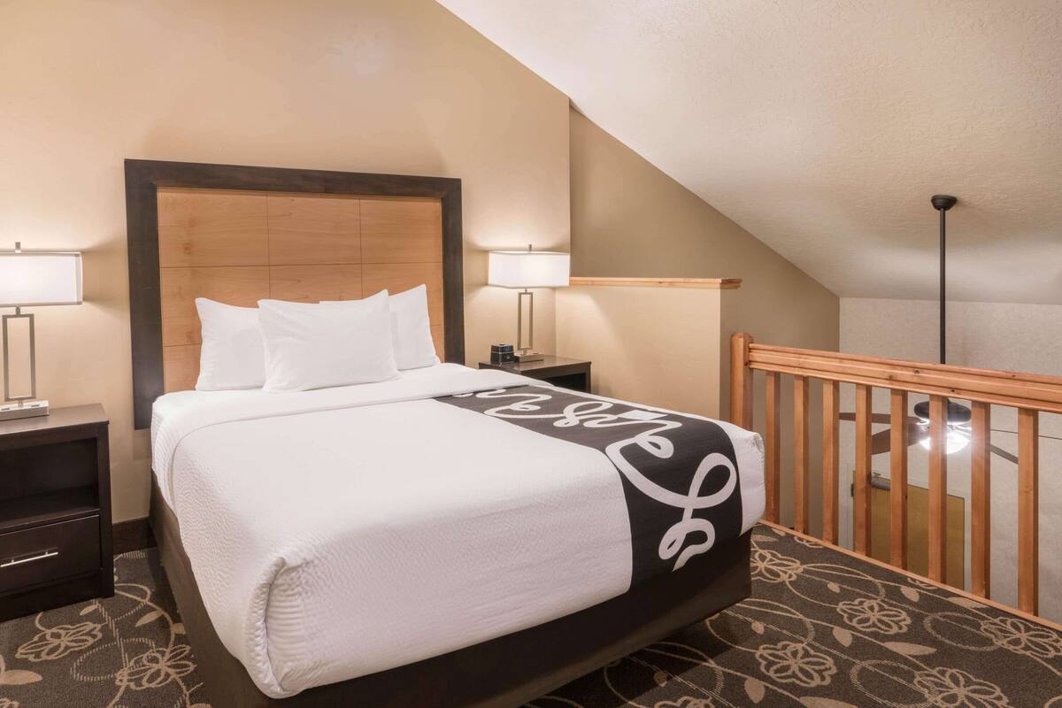 A hotel room with a bed, nightstands, and a wooden railing.