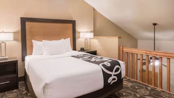 A hotel room with a bed, nightstands, and a wooden railing.