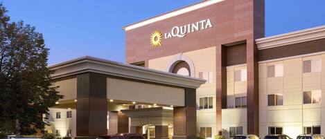 A hotel with a prominent 'La Quinta' sign, multiple parking spaces, and a modern architectural design.