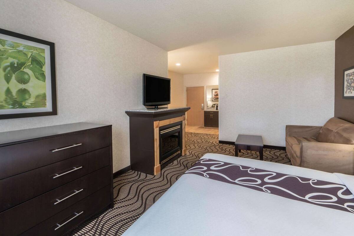 A hotel room with a bed, a dresser, a television, and a small table.