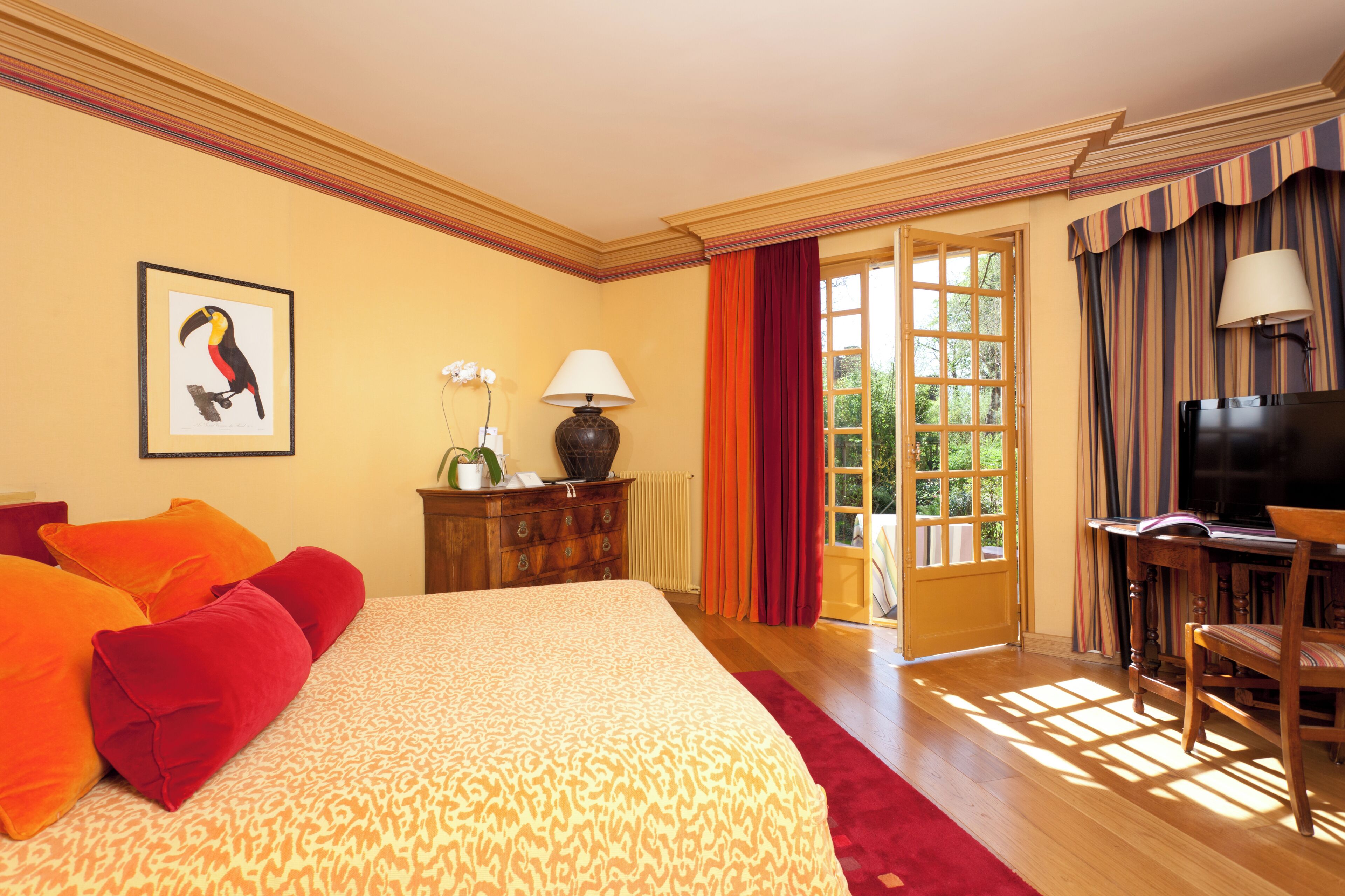 A hotel room with a large bed, a desk with a chair, a television, and a window with curtains.