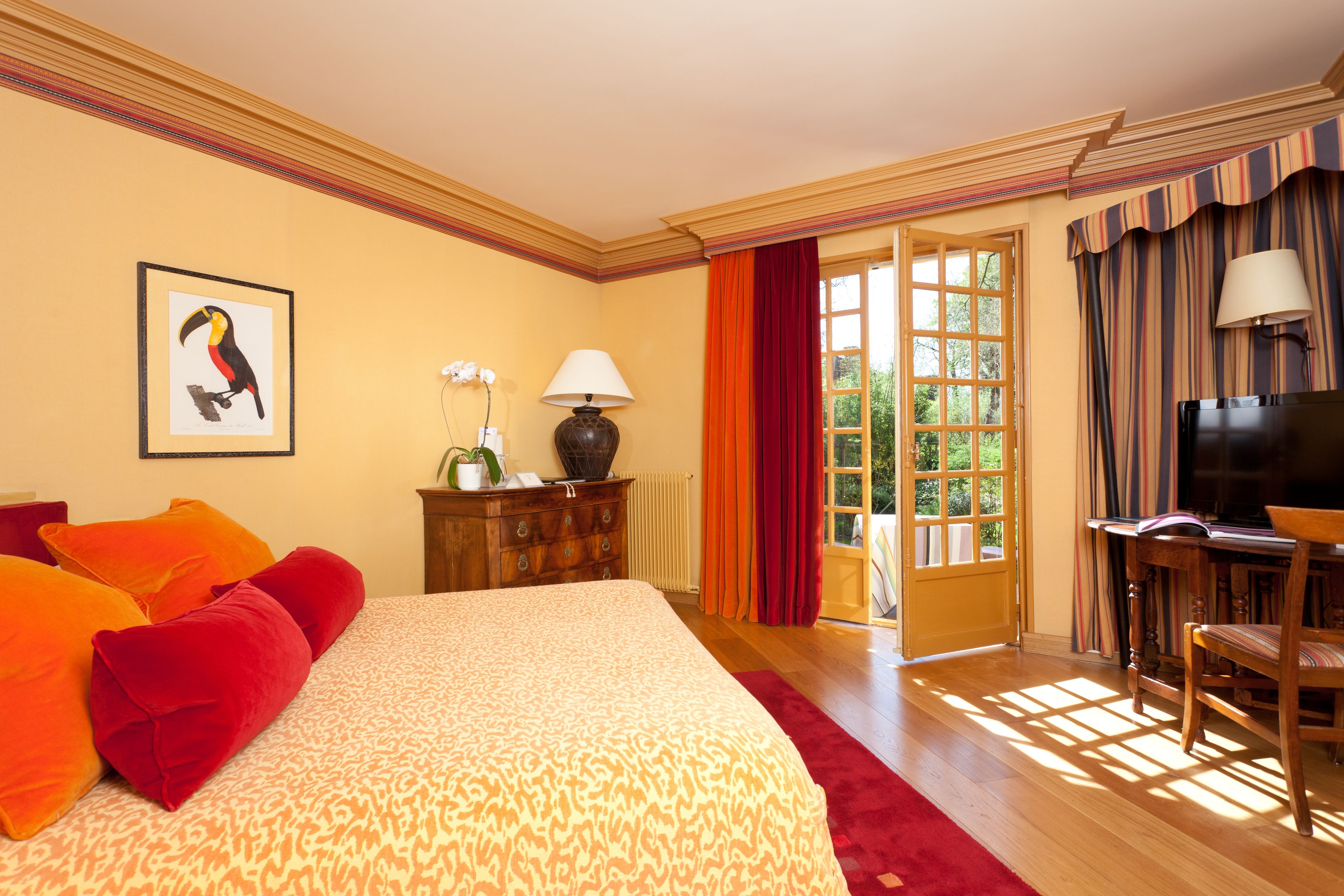 A hotel room with a large bed, a desk with a chair, a television, and a window with curtains.