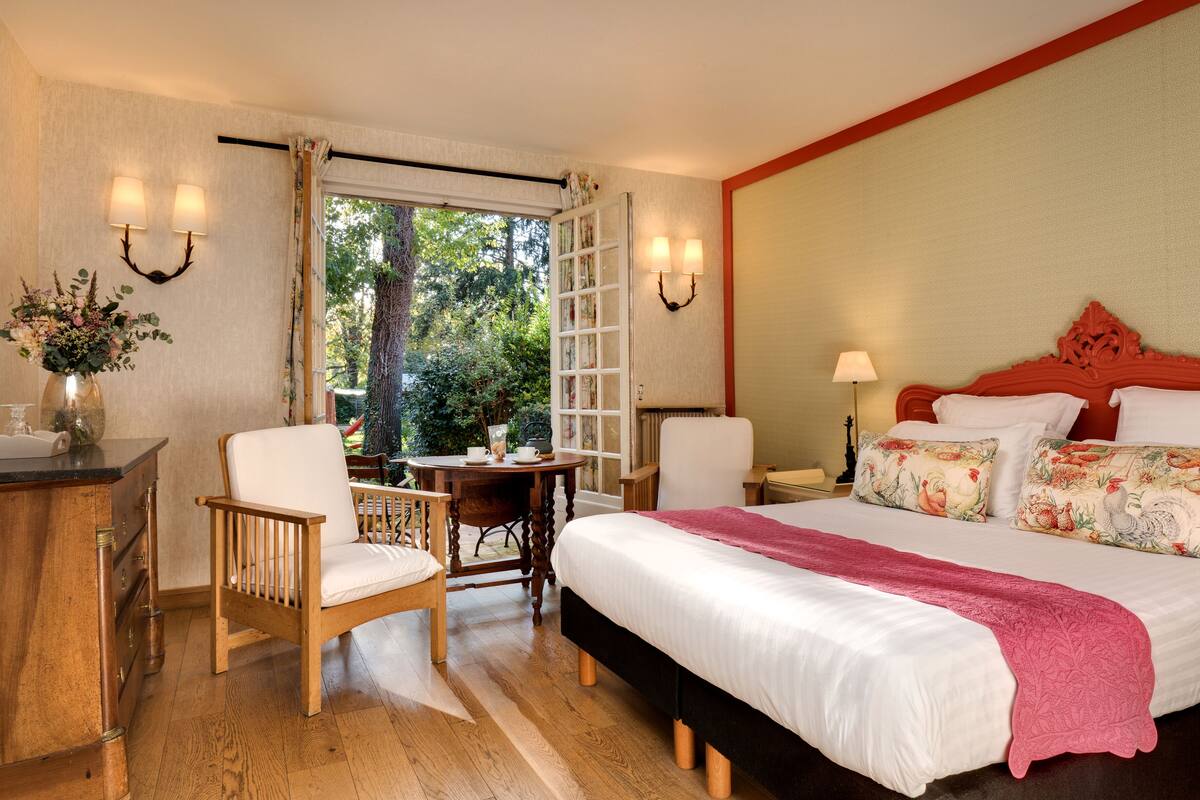 A hotel room with a bed, a desk, a chair, and a view of the outdoors.