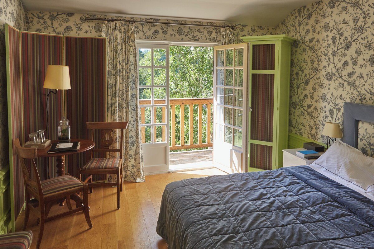 A bedroom with a bed, a desk with a chair, a nightstand, and a green wardrobe.