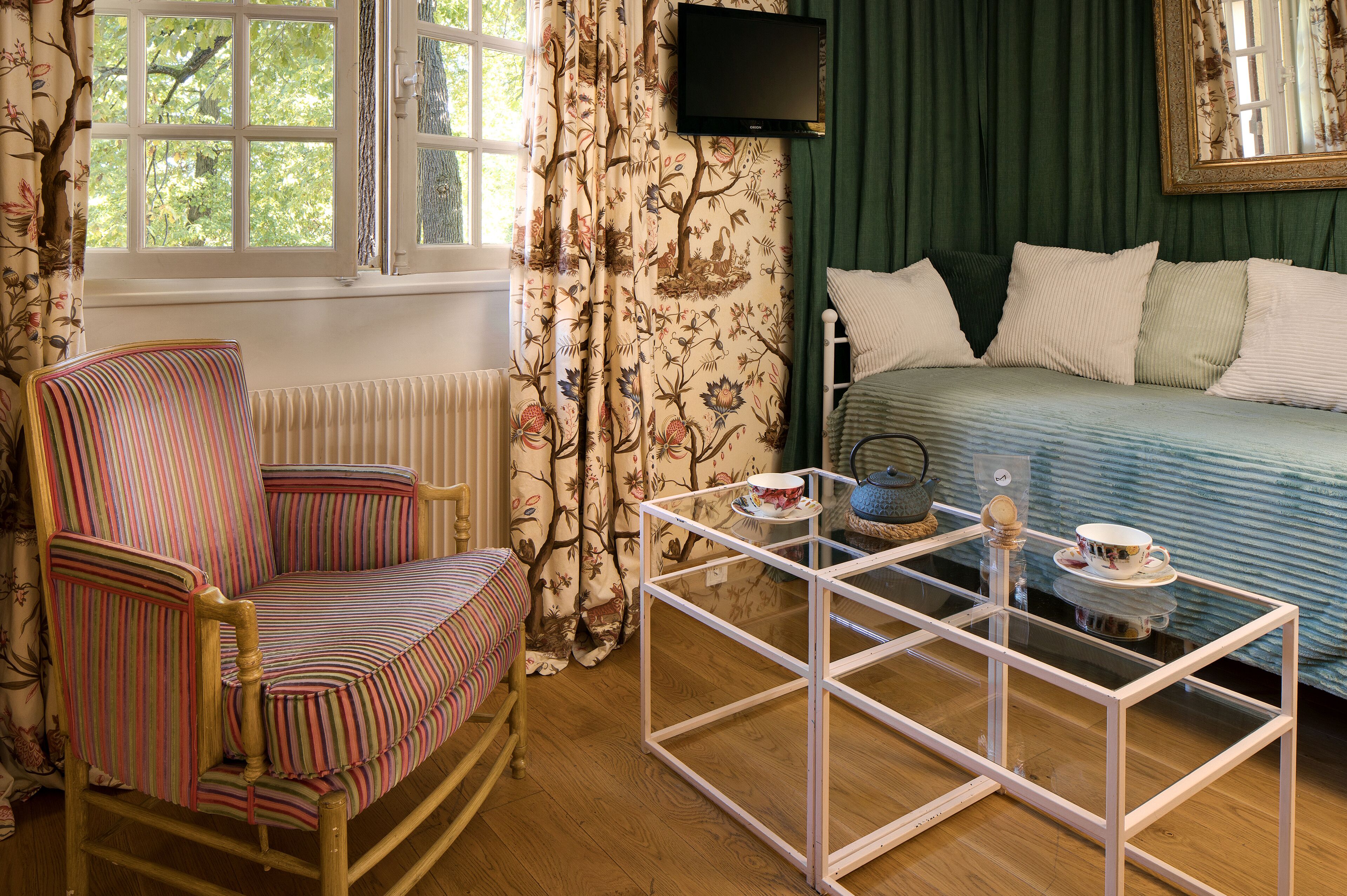 Una habitación con cama, una silla, una mesita de centro de vidrio y televisión.