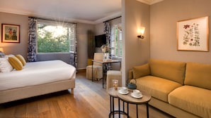 A room with a bed, a sofa, a small table with cups and a teapot, and a window with curtains. - CAZAUDEHORE Hôtel Restaurant Gastronomique Terrasse et Jardins (Saint-Germain-en-Laye)